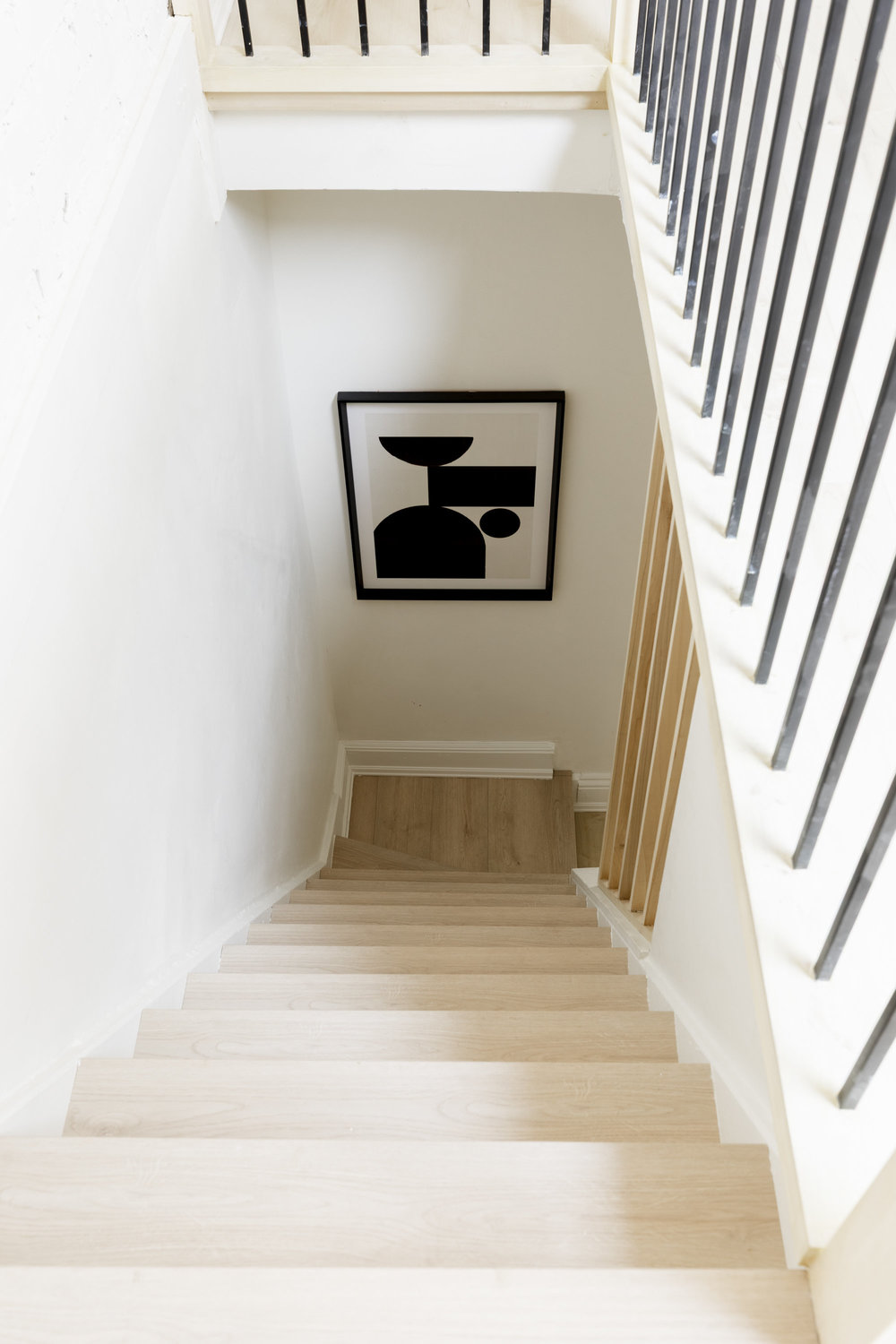 Bright staircase with light wood steps and framed artwork