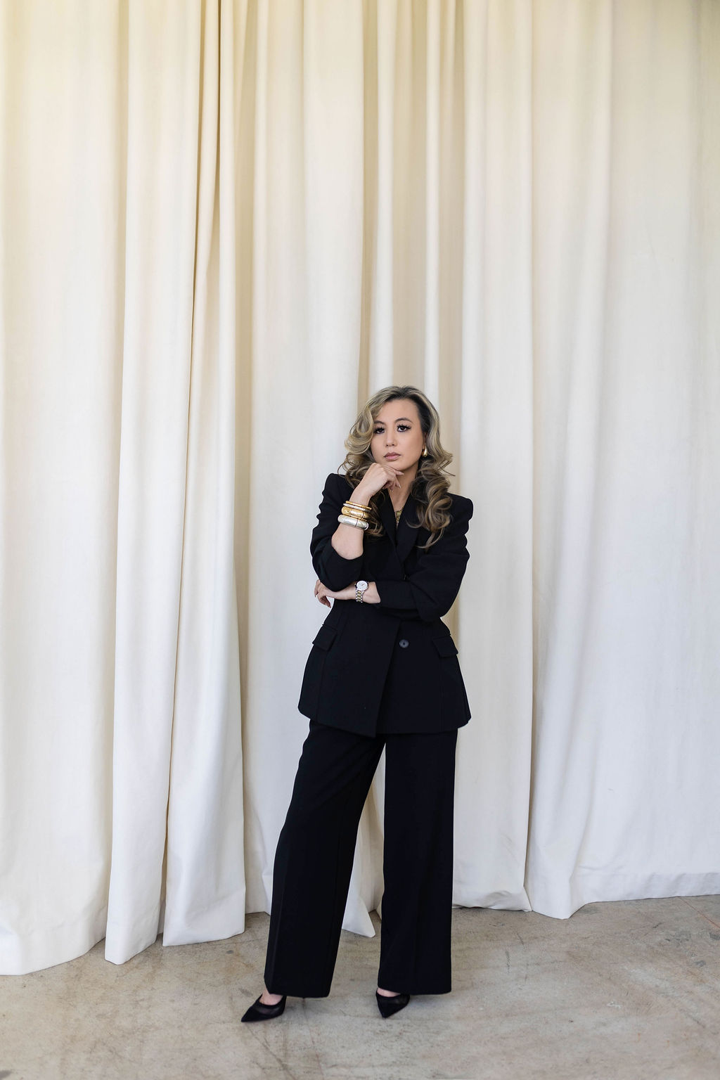 Tramy Nguyen, founder of Envision, in a black suit against cream curtains